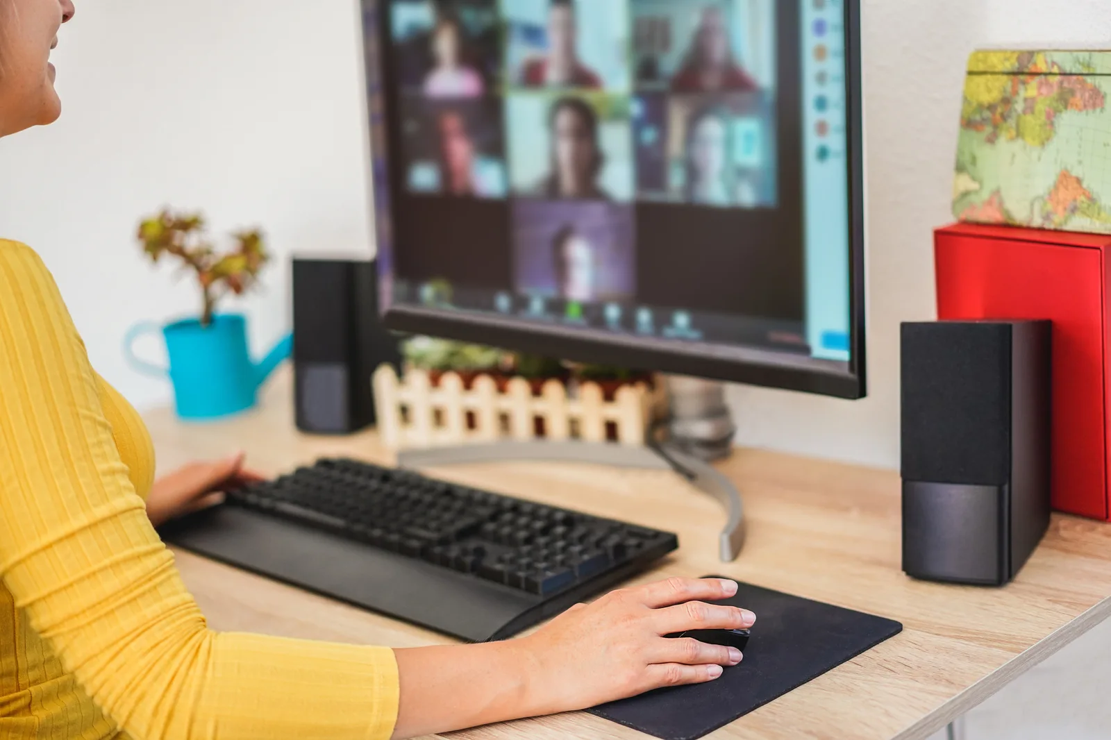 A woman at her desk on a video call, a grid of other faces on the screen